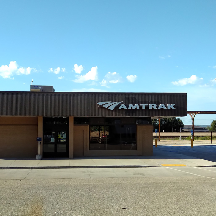 One story train station with flat black metal roof.