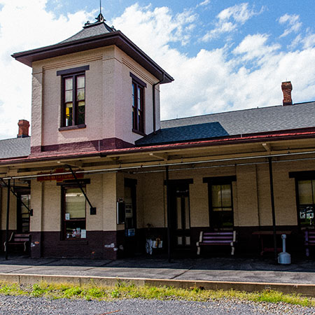 Small brick railroad depot with a two-story tower.