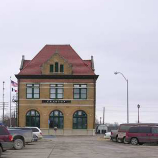 Building fronted by parking lot with cars.