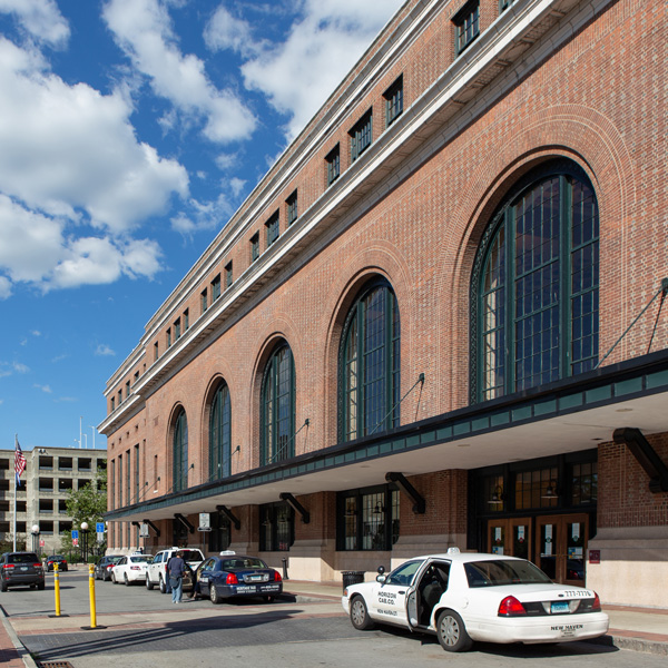 Brick rail station featuring large round arch windows and entryways.