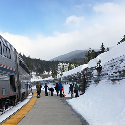 Passengers on a platform with piles of snow to the side.