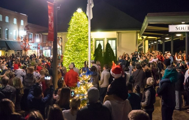 Crowd gathered at around a holiday tree at the Southern Pines depot.