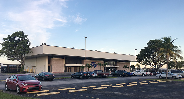 Miami station, built of concrete block and glass, surrounded by trees including palm trees.