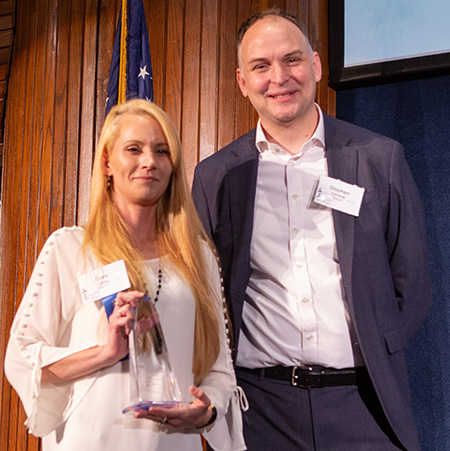 Woman holding trophy standing next to a man.