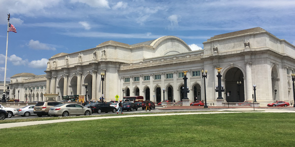 Panoramic view of Washington Union station, a neoclassical building constructed of white marble and featuring archways and columns.