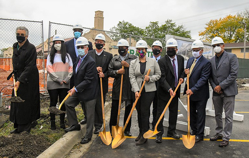 Group of people holding shovels and wearing hardhats.