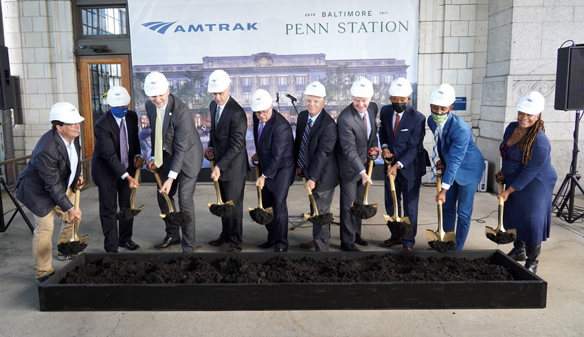 Men and women stand in a line wearing hardhats.