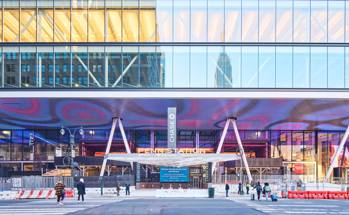 An entrance to a train station with a broad canopy and colorful lighting.