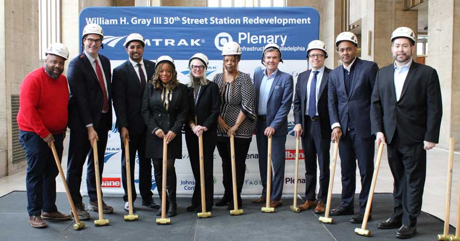 A group poses with sledgehammers and hard hats.