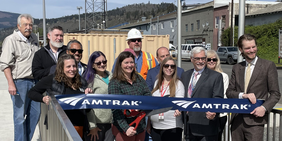 A group holds a ribbon at a train station.