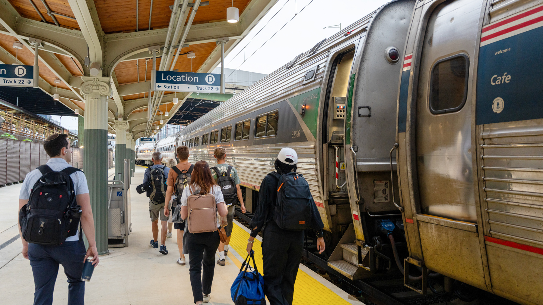 Passengers walk down a platform to board a train